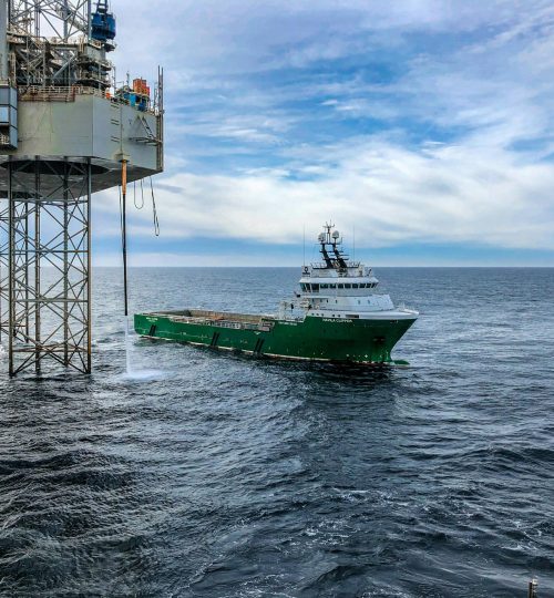Supply vessel approaching offshore oil platform in Danish waters, showcasing maritime industry.